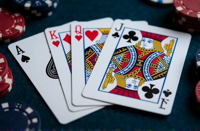 Aufgef&auml;cherte Spielkarten mit Ass und K&ouml;nig neben Chips auf dunklem Filz - Jackpot- und Kartenspiele bei V.Vegas